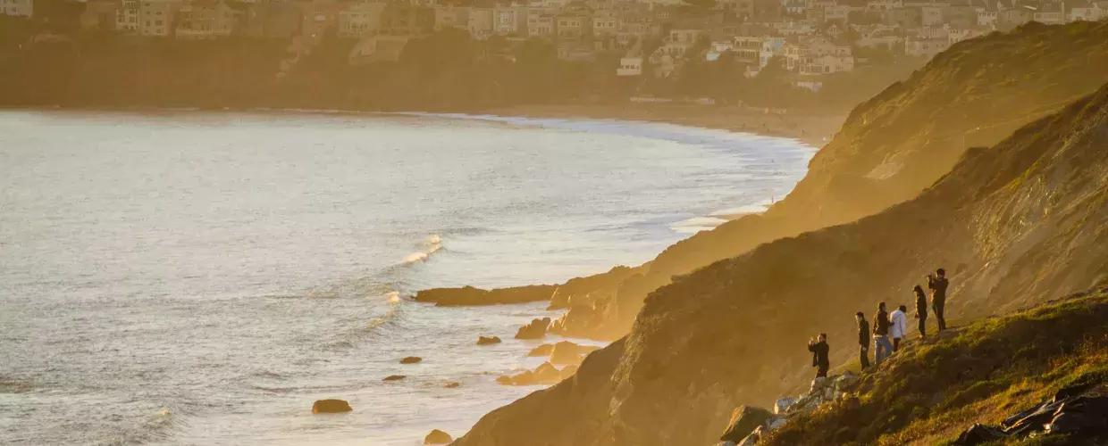 在贝博体彩app的普雷西迪奥，一群人站在海边的悬崖边看日落.