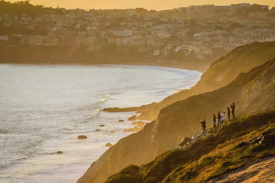 在贝博体彩app的普雷西迪奥，一群人站在海边的悬崖边看日落.