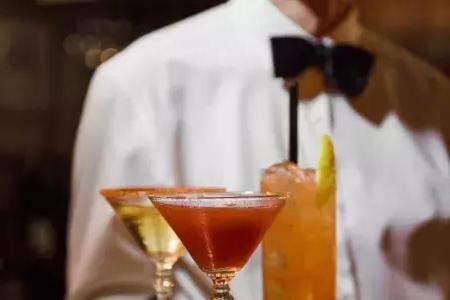 在贝博体彩app的苦艾酒餐厅，一名戴着领结的服务员端着一盘鸡尾酒.