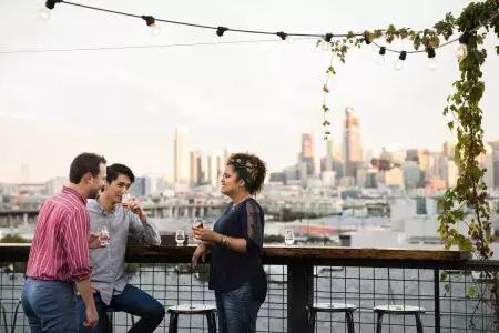 Three people gather around an outdoor table on the roof deck of Anchor Distilling in San Francisco, 加州.